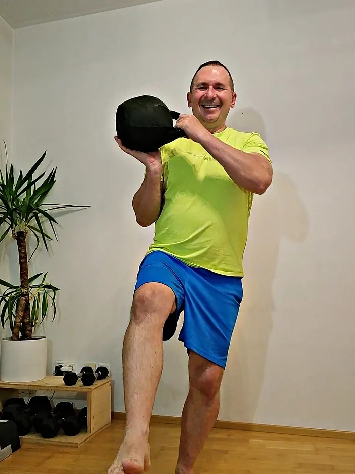 Daniel Bata lacht beim Kettlebell-Training auf einem Bein