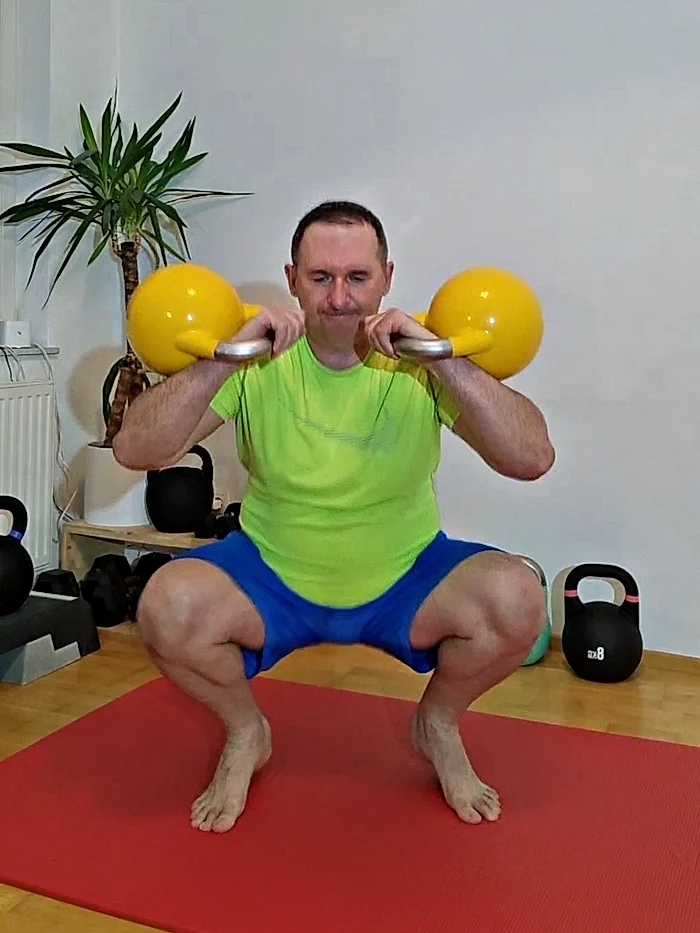 Daniel Bata in der tiefen Hocke mit zwei Kettlebells