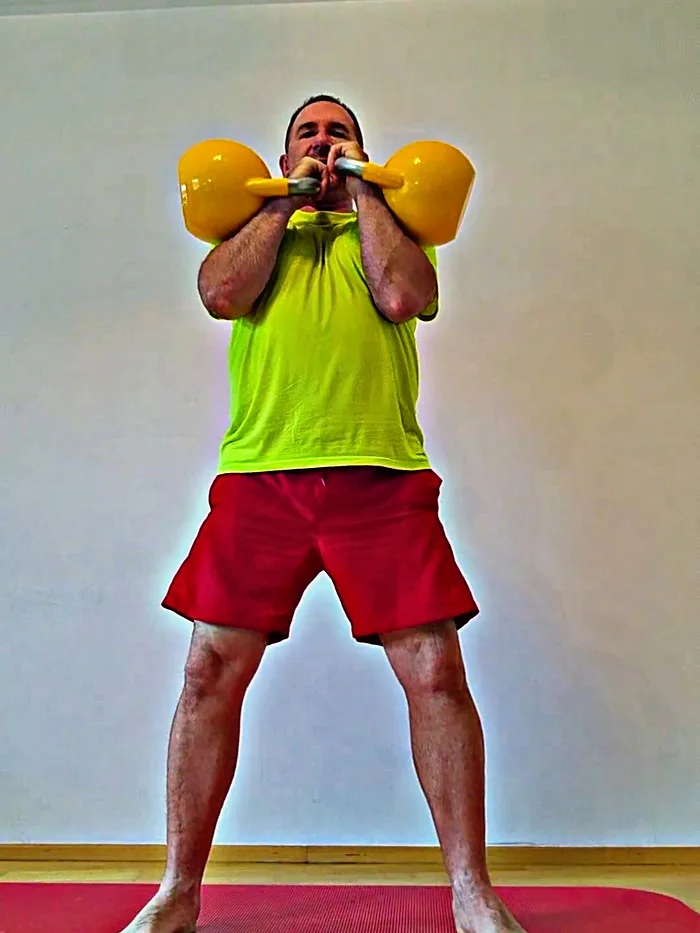 Daniel Bata hält zwei Kettlebells vor der Brust