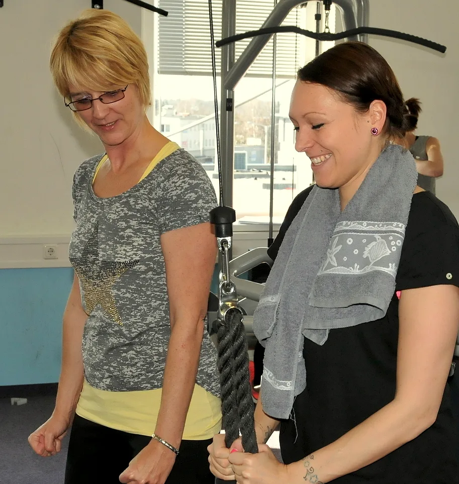 Trainerin begleitet eine Teilnehmerin beim Training am Seilzug
