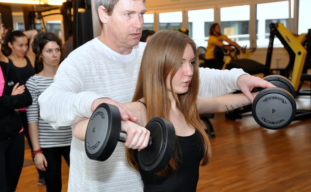 Trainer korrigiert eine Teilnehmerin beim Kurzhanteltraining